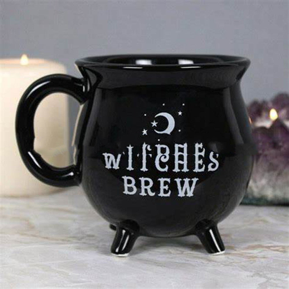 Black Witches Brew cauldron mug with moon and stars design styled with candle and crystal