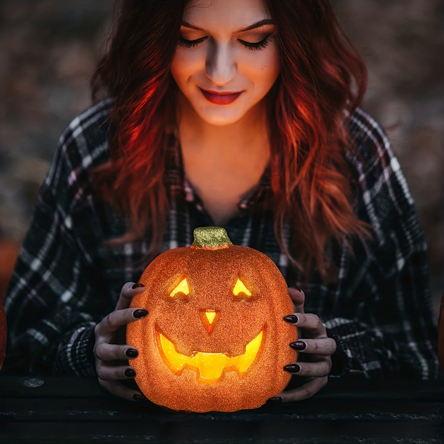 Woman holding a light-up orange pumpkin lantern Halloween decoration