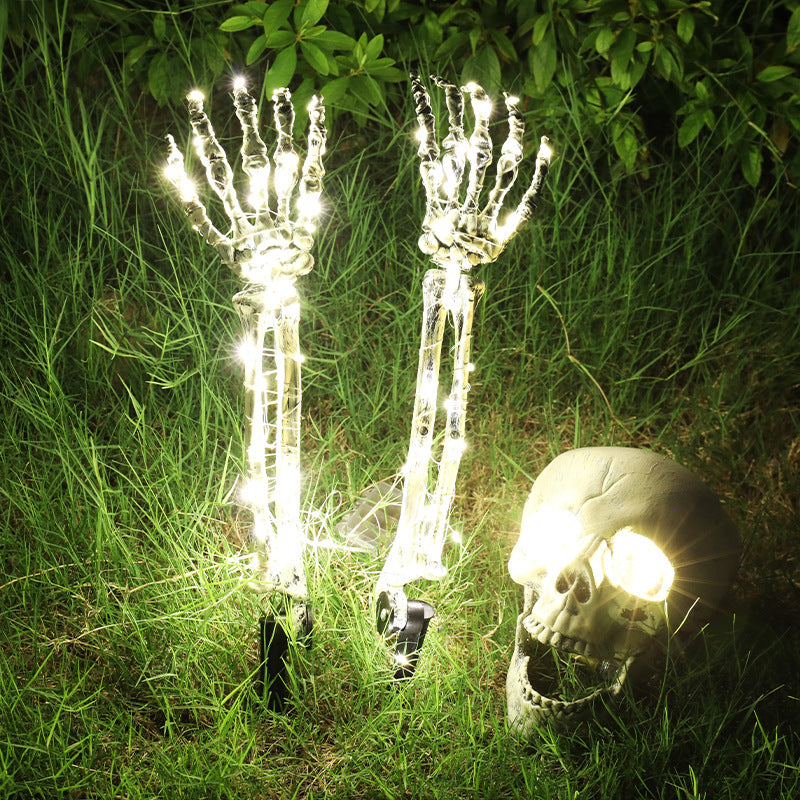 Three Pieces Warm White Halloween LED skeleton hand and skull set glowing in grass at night