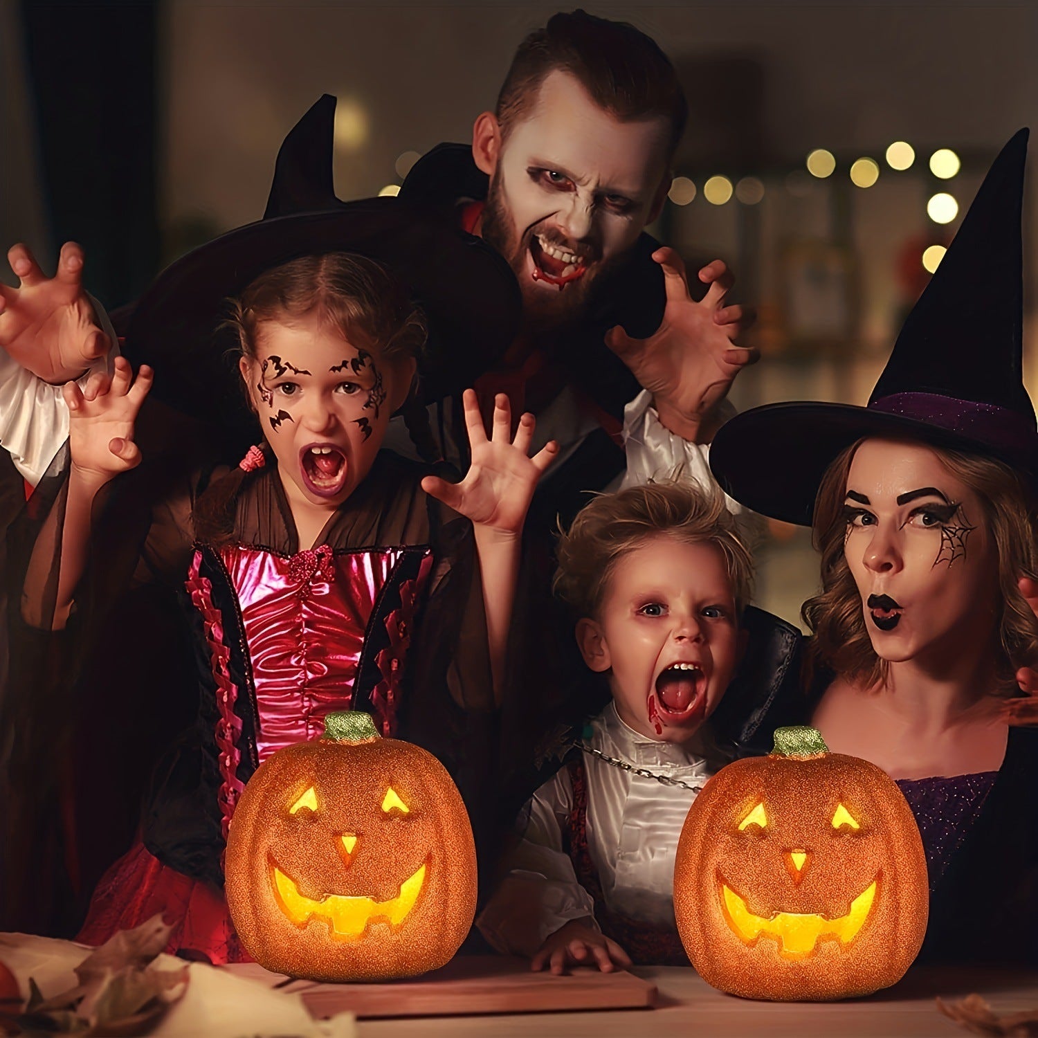 Family in Halloween costumes with two light-up jack-o-lantern pumpkin decorations
